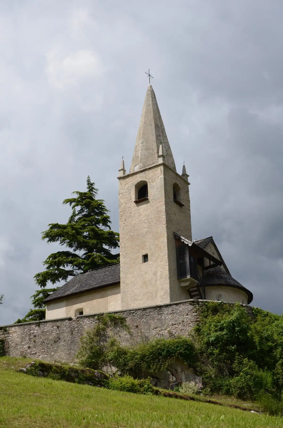 Chiesa con campanile in pietra su un colle erboso