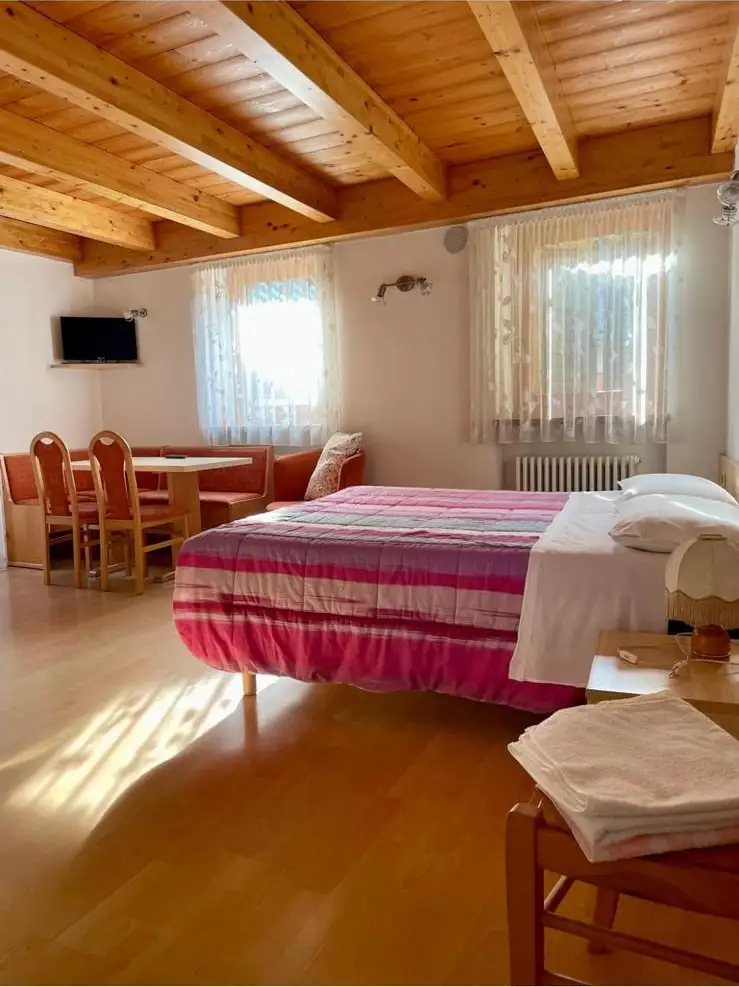 Il letto matrimoniale e la zona pranzo dell’alloggio con angolo cottura