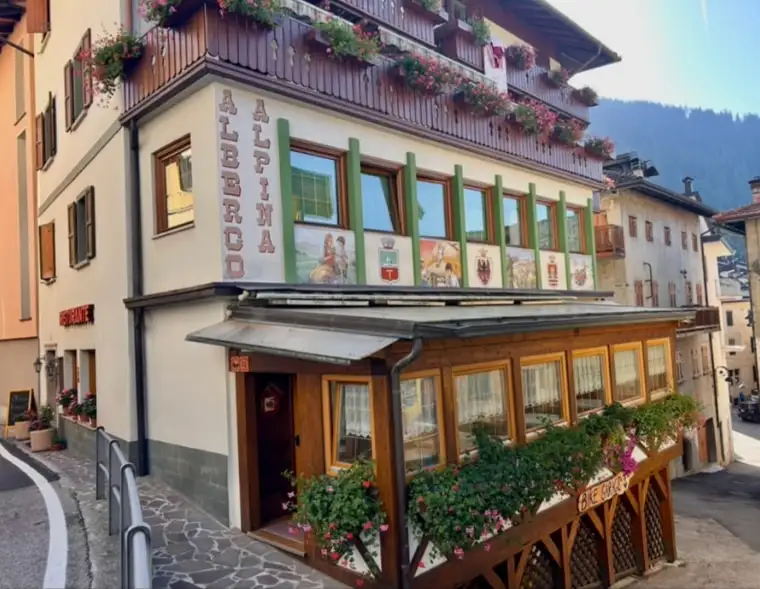 La facciata dell’Albergo Alpina con i balconi e la veranda fioriti