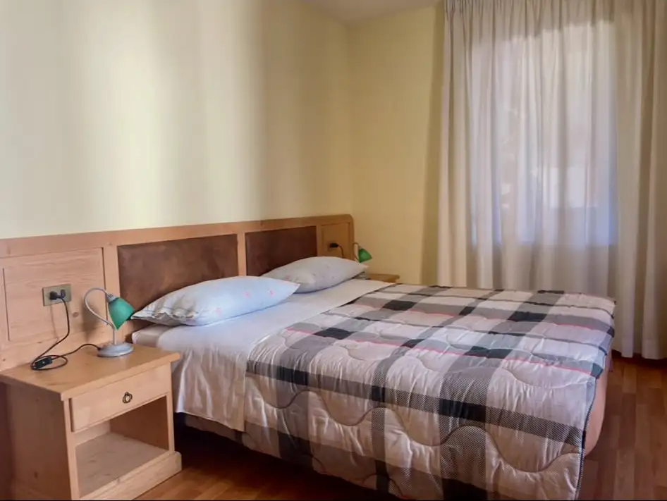 Camera matrimoniale dell’albergo con copriletto a quadri e comodini in legno