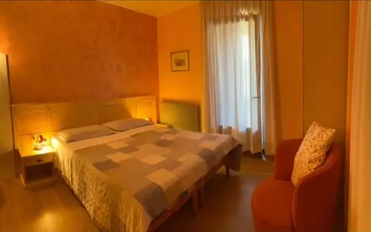 La prima camera della quadrupla comunicante, con letto matrimoniale e poltrona