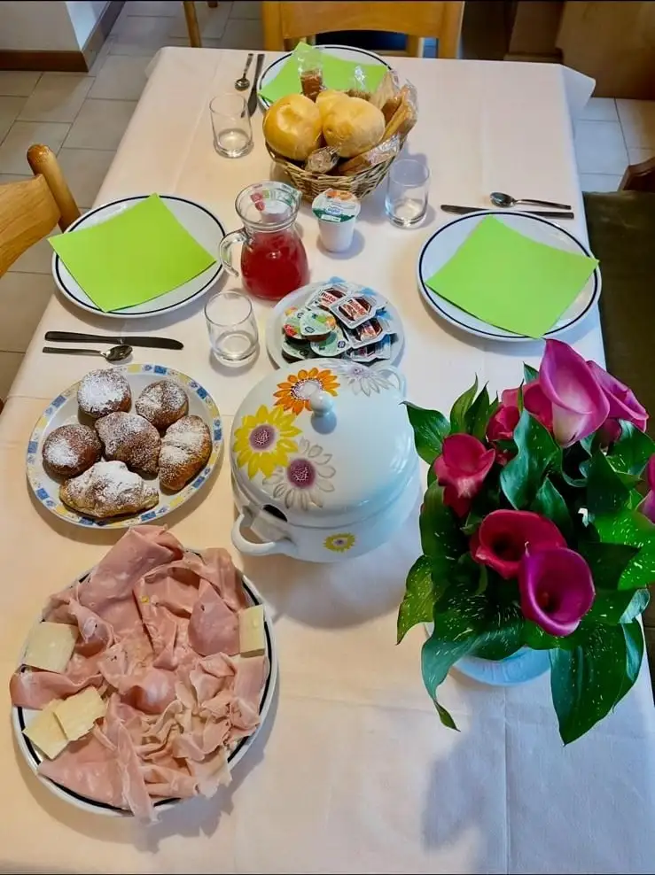 La tavola della colazione con pane, frutta, dolci e affettati